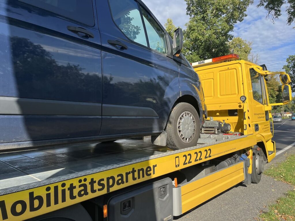 Ein Blauer kleinbus auf der Ladefläche eines gelben ADAC Abschleppautos.